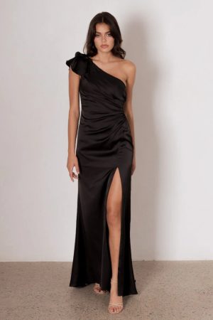 Model wearing the Kiko bridesmaid dress by Tania Olsen in light satin, featuring a one-shoulder neckline with tiered flute sleeve, draped waist, and A-line skirt with high-leg split.