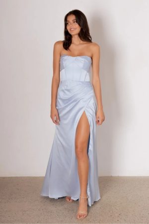 Model wearing the Layana bridesmaid dress by Tania Olsen in light satin, featuring a strapless corset bodice, draped waist, and A-line skirt with high-leg split.