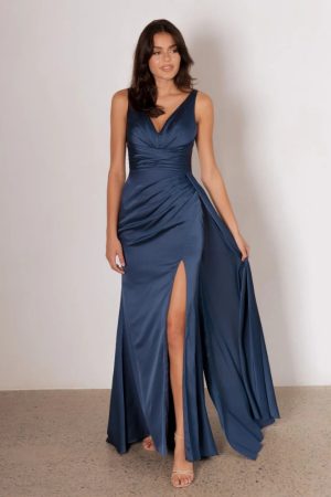 Model wearing the Petra bridesmaid dress by Tania Olsen in light satin, featuring a V-neckline, draped waist, and floor-length skirt with high-leg asymmetrical split.